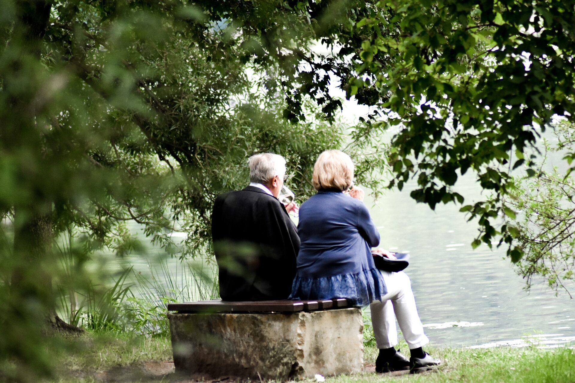 old couple sitting near lake